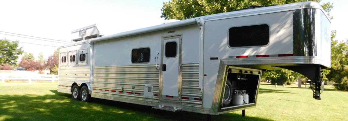 A Logan Coach Gooseneck Horse trailer parked on the grass